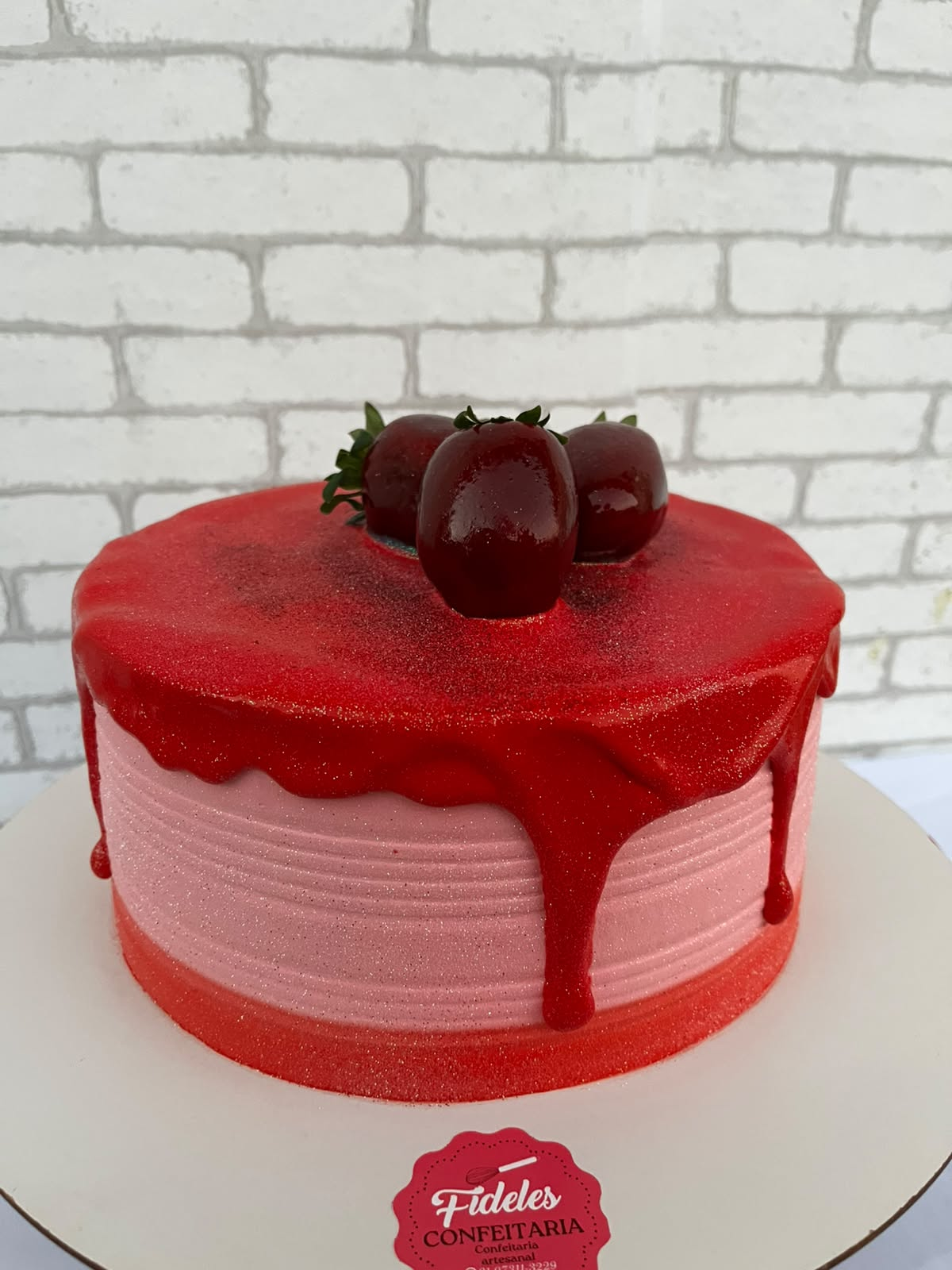 Bolo rosé com calda vermelha e morangos